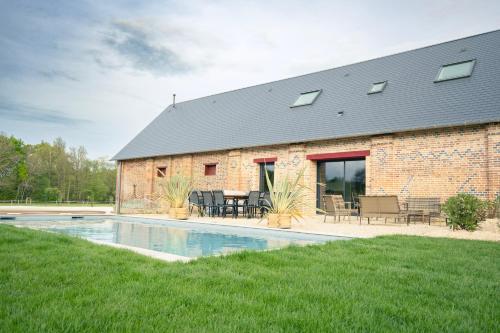 - un bâtiment en briques avec une piscine en face dans l'établissement Les Longères de Montfranc - Gîte, à Pierrefitte-sur-Sauldre