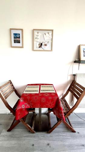 une table rouge dans une pièce avec deux chaises dans l'établissement Sunny Studio with Balcony - buttes Chaumont park, à Paris