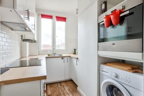 une cuisine avec des armoires blanches et une laveuse et une sécheuse dans l'établissement GuestReady - Family Retreat near Paris, à Saint-Denis