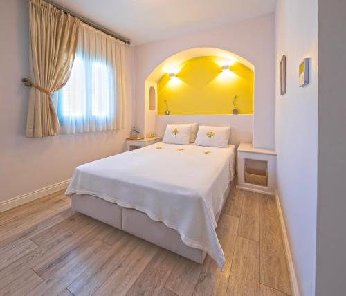 a bedroom with a white bed and a window at Sigacik Gardenya Buti̇k Otel in Siğacık