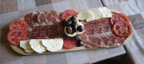a plate of meats and cheese and tomatoes on a table at Camp River in Virpazar
