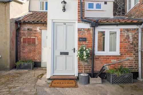 a brick house with a white door and a window at 3a Childs Yard, Southwold in Southwold