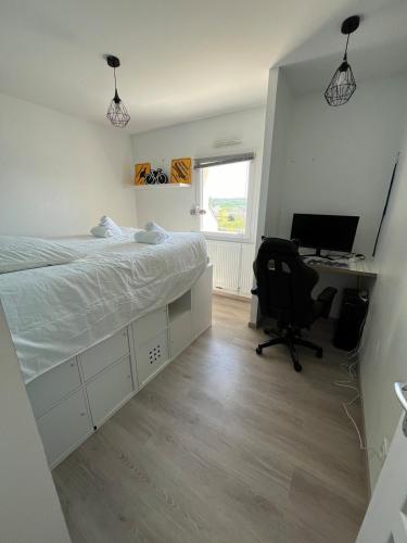 a bedroom with a bed and a desk with a computer at La P'tite Huguette in Port-en-Bessin-Huppain