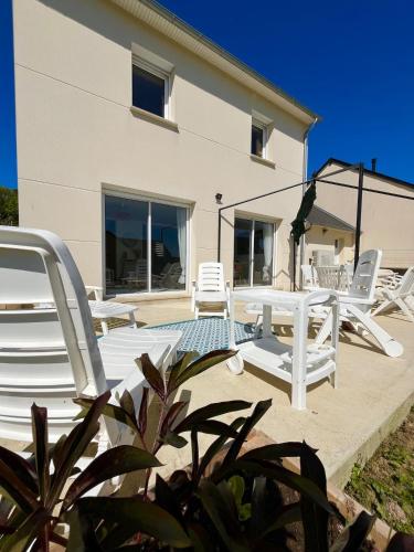 a patio with white lounge chairs and a building at La P'tite Huguette in Port-en-Bessin-Huppain