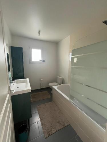 a bathroom with a tub and a toilet and a sink at La P'tite Huguette in Port-en-Bessin-Huppain