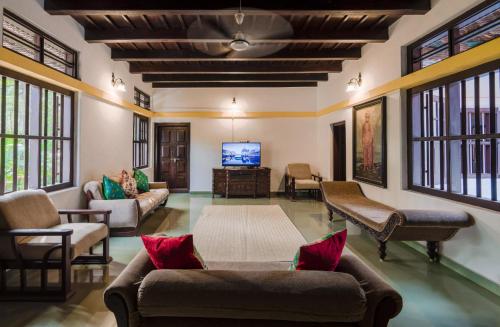 a living room with couches and a flat screen tv at SaffronStays Amaya - 5BR 300-year-old Kerala-style heritage home near Kannur Airport in Irikkūr