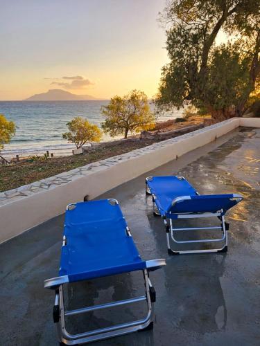 two blue beach chairs sitting next to the ocean at Aether Beach House in Foinikion