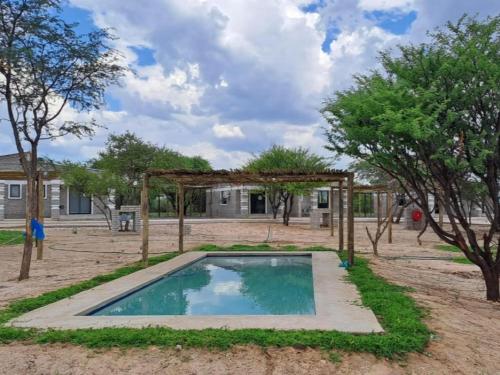 una piscina all'aperto con arbore e alberi di Ghanzi Travel and Accommodation a Ghanzi