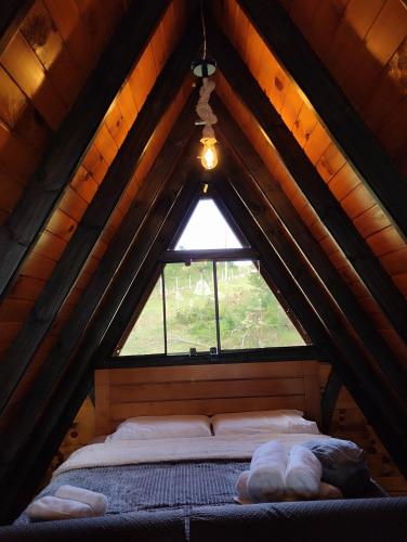 a bed in a wooden attic with a window at Rancho dos lagos in Campo Alegre