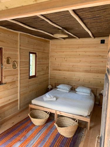 a bed in a wooden cabin with two baskets at Soul Farm Algarve - Glamping & Farm Houses in Aljezur
