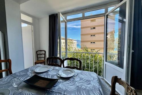 une table de salle à manger avec vue sur un balcon dans l'établissement Grand T3 avec vue mer - Proche plage - Parking & AC, à Ajaccio