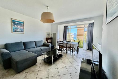 un salon avec un canapé bleu et une table dans l'établissement Grand T3 avec vue mer - Proche plage - Parking & AC, à Ajaccio