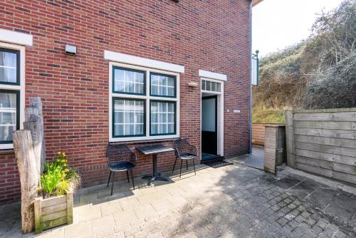 two chairs and a table in front of a brick building at Duinhotel Haga in Zoutelande