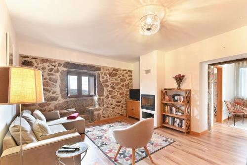 a living room with a stone wall at Casa do Alfaiate - Piscina & Barbecue - Gerês in Rego