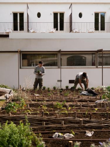 two men working in a garden in front of a building at Hostal Empúries in L'Escala