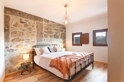 a bedroom with a bed with a stone wall at Casa do Alfaiate - Piscina & Barbecue - Gerês in Rego