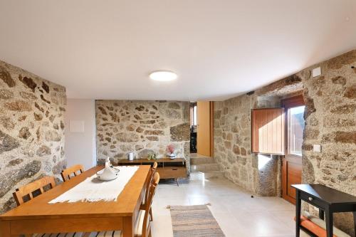 a dining room with stone walls and a table and chairs at Casa do Alfaiate - Piscina & Barbecue - Gerês in Rego