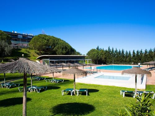 ein Pool mit Stühlen und Sonnenschirmen sowie ein Gebäude in der Unterkunft VitaSol Park in Lagos