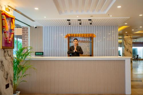 a woman standing behind a counter in a lobby at Velvet Luxe Hotel in Jogīkuti