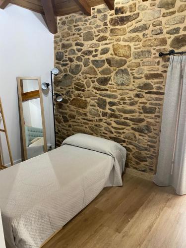 a bedroom with a stone wall and a bed at Casa Erundina in Camariñas