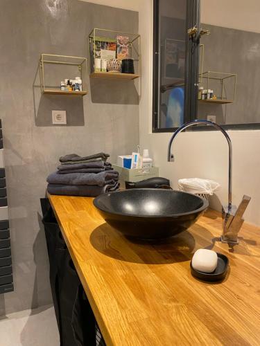 La salle de bains est pourvue d'un lavabo noir sur un comptoir en bois. dans l'établissement Les Precheurs Hideaway, Chic Retreat in Aix Historic Heart, à Aix-en-Provence