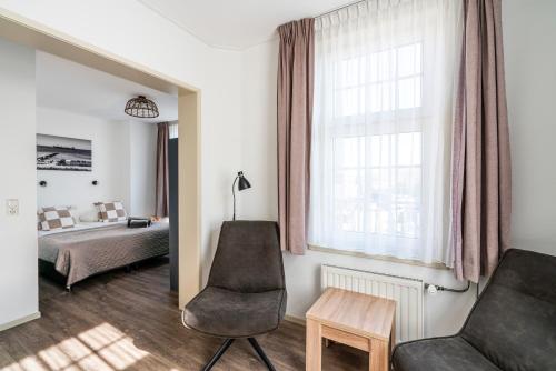 a bedroom with a bed and a couch and a chair at Duinhotel Haga in Zoutelande