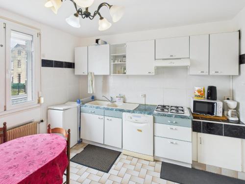 une cuisine avec des armoires blanches, un évier et un micro-ondes dans l'établissement Maison CARPE DIEM, à Romilly-sur-Seine