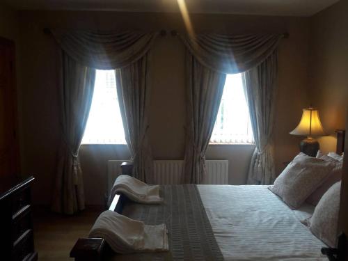 a bedroom with a large bed with two windows at Carndonagh - 3-Bedrooms - Sleeps 6 7 - Garden in Carndonagh