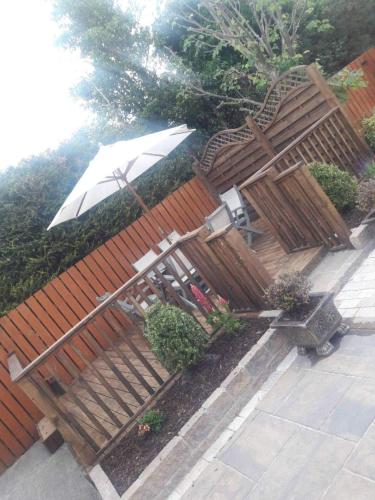 a wooden fence with an umbrella and chairs at Carndonagh - 3-Bedrooms - Sleeps 6 7 - Garden in Carndonagh