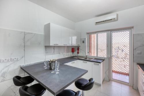a kitchen with a table and black chairs at Amazing apartment with pool in Malta in Is-Swieqi