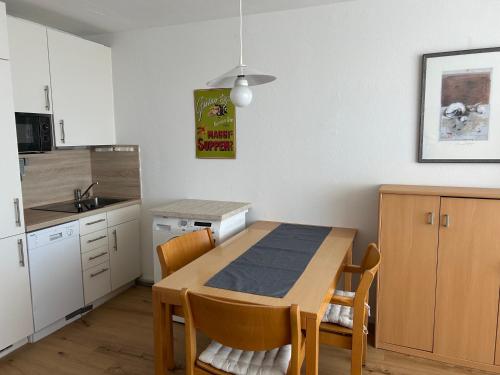 a kitchen with a wooden table and a kitchen with white cabinets at Ferienwohnung Predigtstuhl Resort in Sankt Englmar