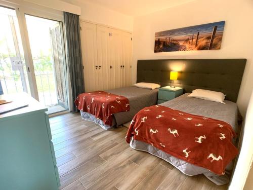 ein Schlafzimmer mit zwei Betten und einem großen Fenster in der Unterkunft Detached Villa on Balaia Golf Village with Golf & Tennis, walking distance to Beach and many Bars and Restaurants in Olhos de Água