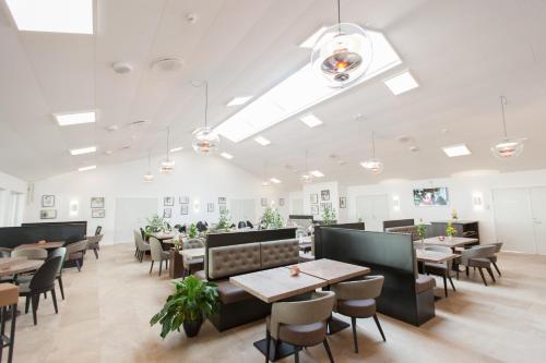 a dining room with tables and chairs and lights at Hotel Falster in Nykøbing Falster