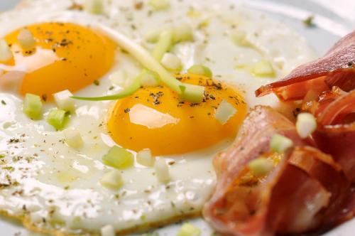 a fried egg and bacon on a white plate at Hotel Sole - Limone in Limone sul Garda