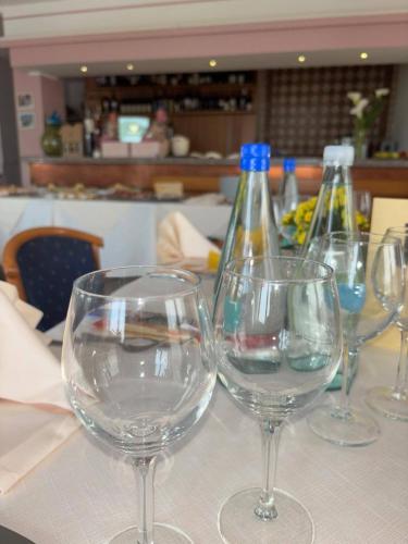 four wine glasses sitting on a table with bottles at Hotel Sporting in Casarsa della Delizia