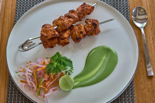 a plate of food with chicken skewers and a pickle at Backwater Ripples Kumarakom in Kumarakom