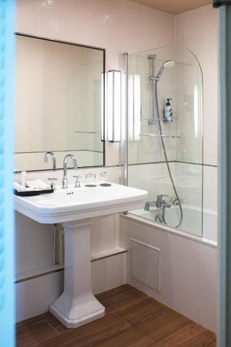 a white bathroom with a sink and a shower at Hotel & Spa Le Grand Monarque, BW Premier Collection in Chartres