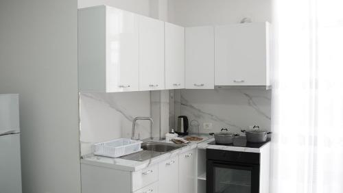 ドゥラスにあるMarina Roomsの白いキャビネットとシンク付きのキッチン