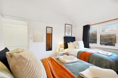 a white room with two beds and a window at Modern Modern Wembley Abode - Parking - Garden - Sleeps 14 in London