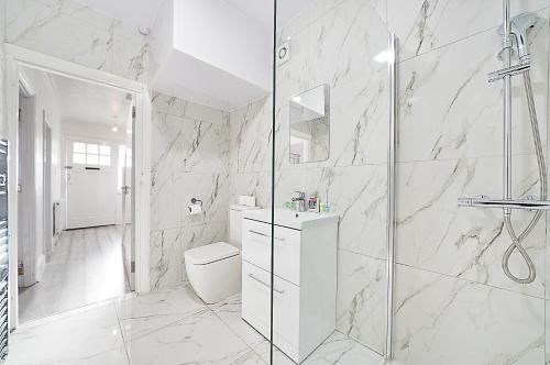 a white bathroom with a shower and a toilet at Modern Modern Wembley Abode - Parking - Garden - Sleeps 14 in London
