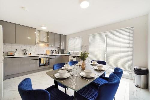 a kitchen and dining room with a table and blue chairs at Modern Modern Wembley Abode - Parking - Garden - Sleeps 14 in London