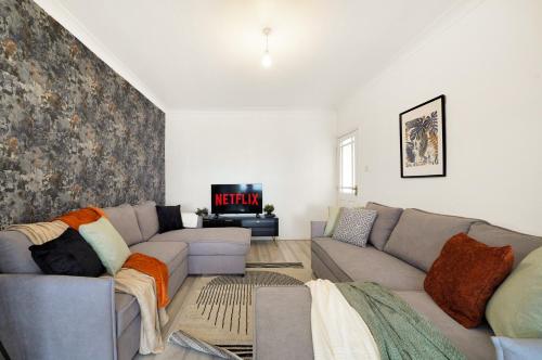 a living room with a couch and a tv at Modern Modern Wembley Abode - Parking - Garden - Sleeps 14 in London