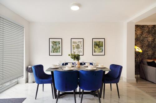 a dining room with a table and blue chairs at Modern Modern Wembley Abode - Parking - Garden - Sleeps 14 in London