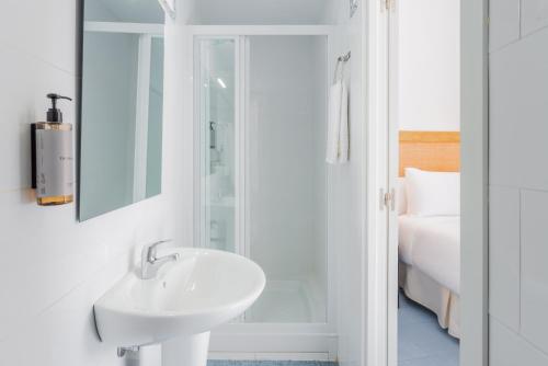 a white bathroom with a sink and a shower at LUTHIA Puerta del Sol in Madrid