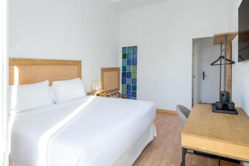 a bedroom with a large white bed and a desk at LUTHIA Puerta del Sol in Madrid