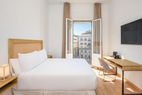 a bedroom with a white bed and a desk and a window at LUTHIA Puerta del Sol in Madrid