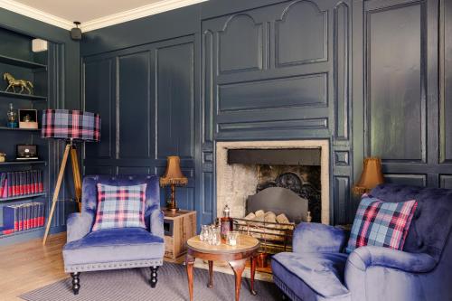 a living room with two blue chairs and a fireplace at Elrick Estate - Elrick House in Newmachar