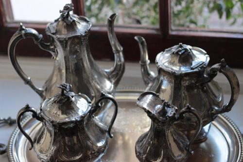 twosilver tea pots and a small pitcher on a plate at Vredenburg Manor House in Somerset West