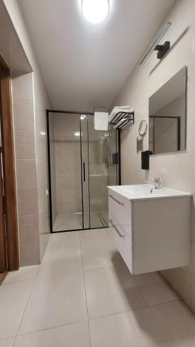 a white bathroom with a sink and a shower at Wiślana 4 in Spytkowice