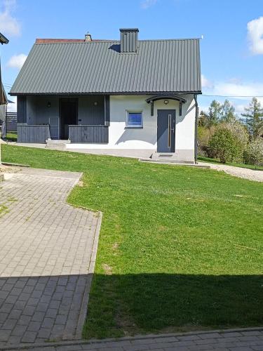 a white house with a blue door and a grass yard at Domek Pod Prehybą -Agroturystyka in Gaboń